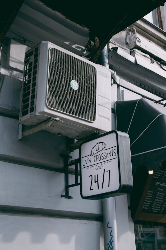 Image of a café sign and air conditioning unit on an urban street corner.